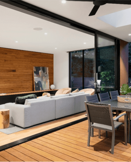 Wnętrze nowoczesnego salonu z dużymi oknami, drewnianym wykończeniem i tarasem z jadalnią na zewnątrz.